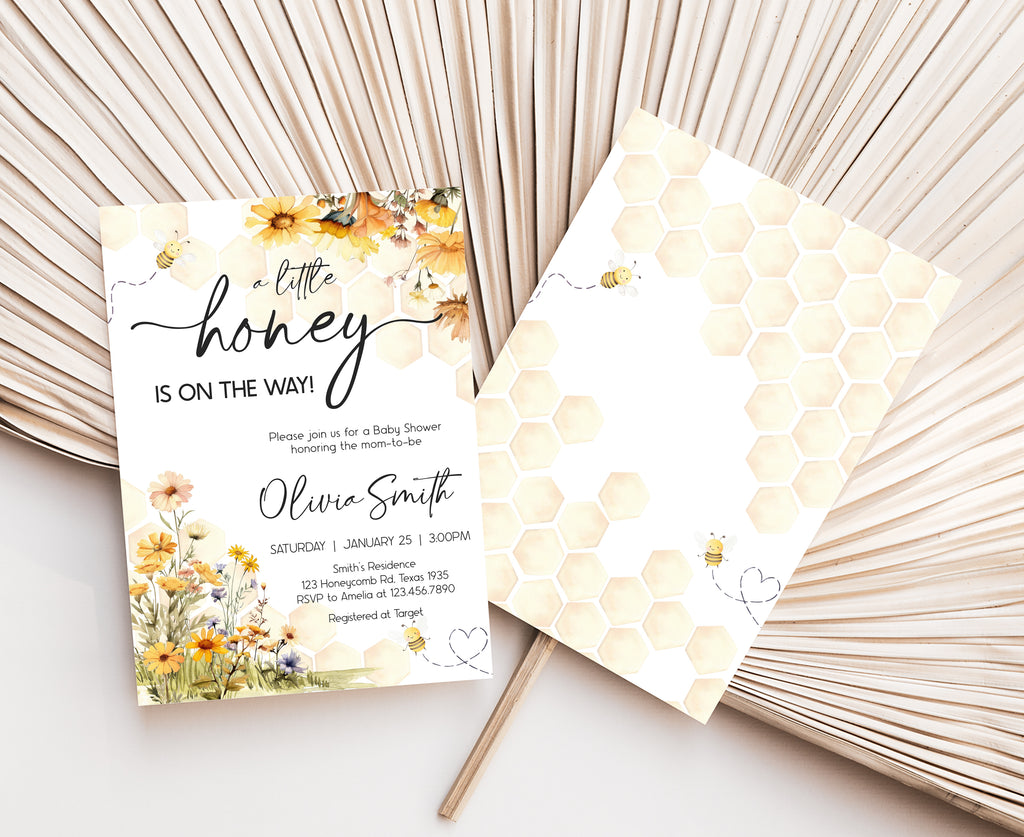 Baby shower invitation with floral design and honeycomb pattern on a white surface.