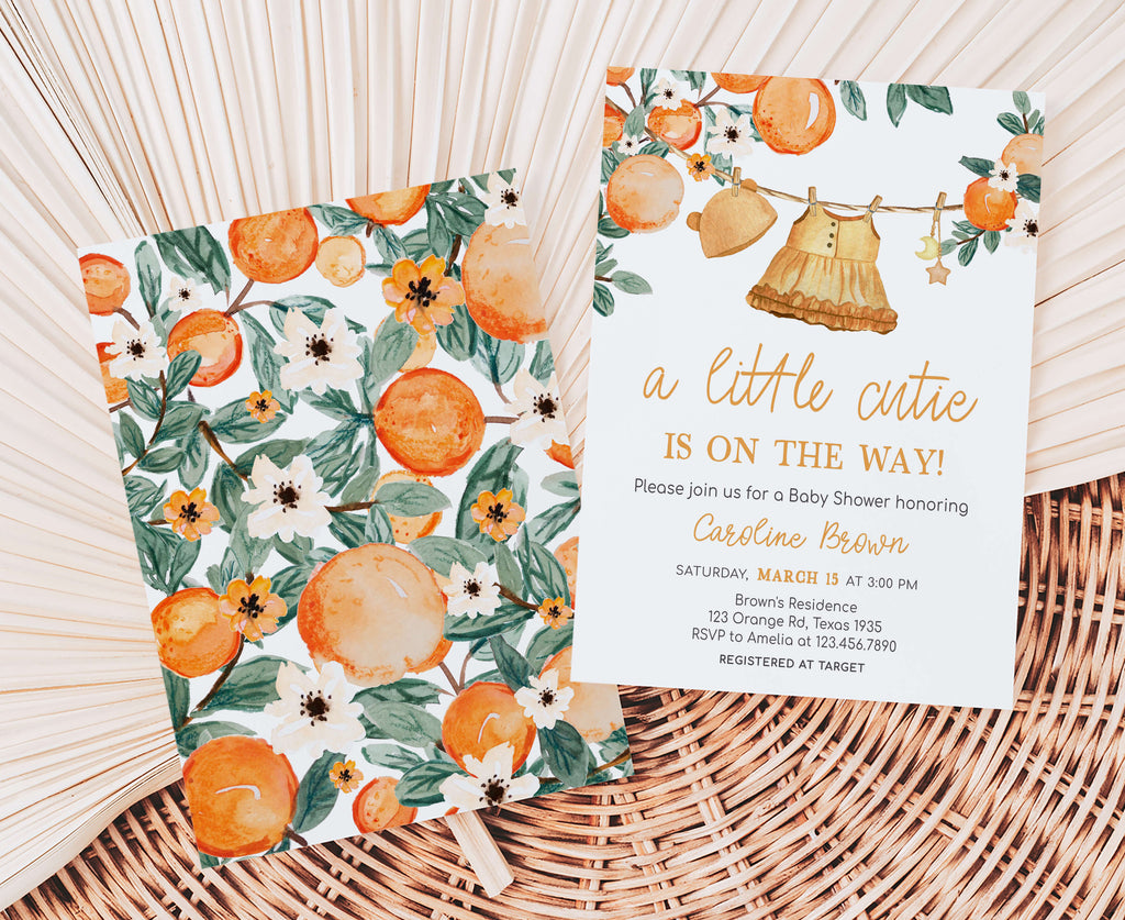 Baby shower invitation with orange-themed design on a woven surface